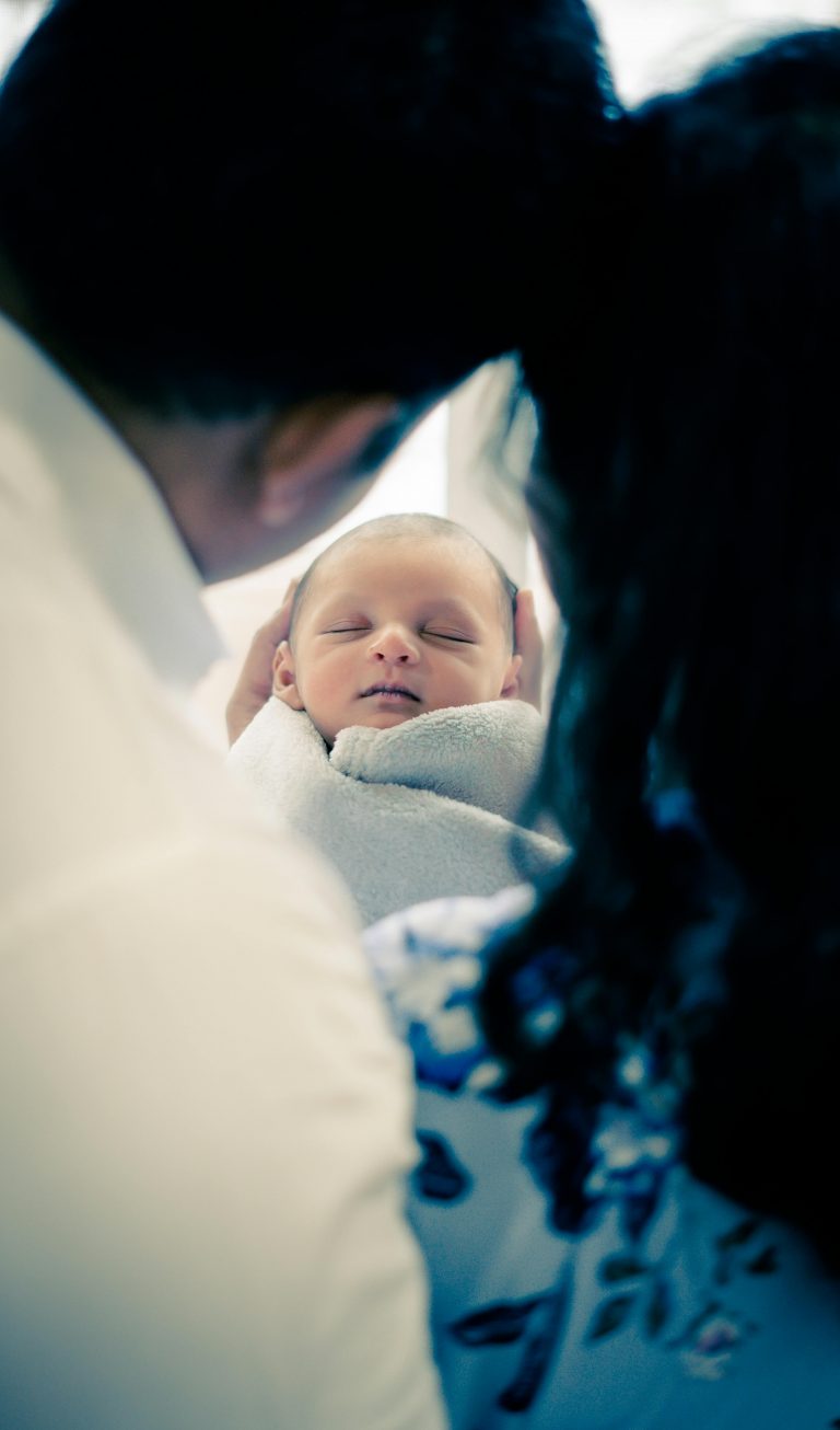 Heartwarming image of parents tenderly holding their sleeping newborn baby, wrapped in a soft blanket.